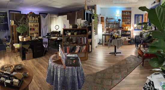 Intimately lit shop space, featuring shelves of metaphysical books, rocks, herbs, and other supplies